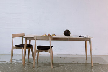 To K5-stole i hvidolieret eg omkring et rektangulært spisebord i træ