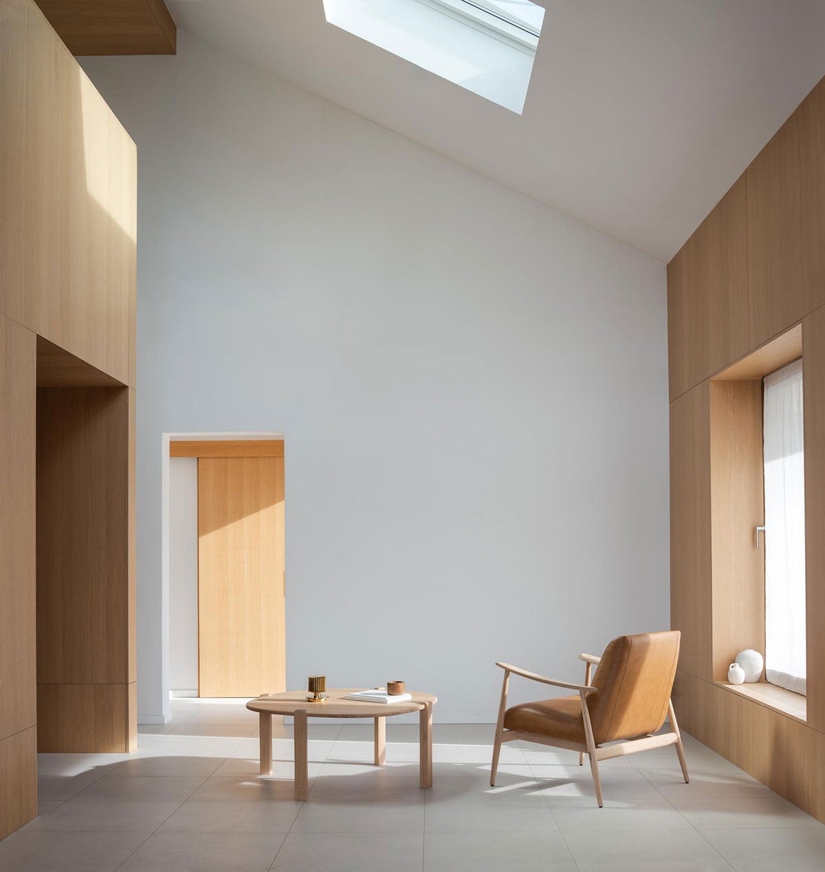 Kulin Sofabord 100x100 i hvidolieret eg ved loungestol i et lyst, åbent rum