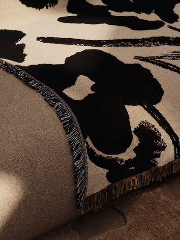 Cilla Tapestry Plaid i farven Off-White/Dark Grape, som ligger casually hen over sofakanten