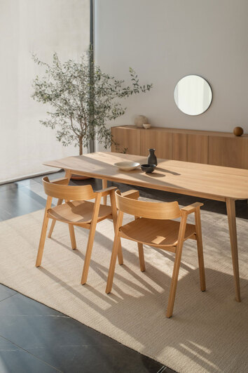 To Flip Stole i natur­lakeret eg omkring et rektangulært spisebord i en spisestue med et beige tæppe