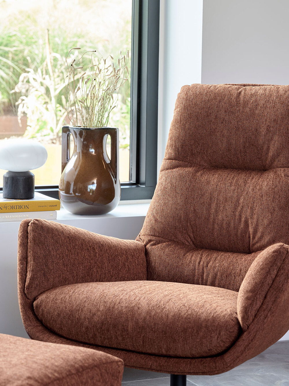 Moro Lænestol i stoffet Copparo Rusty Orange foran et vindue