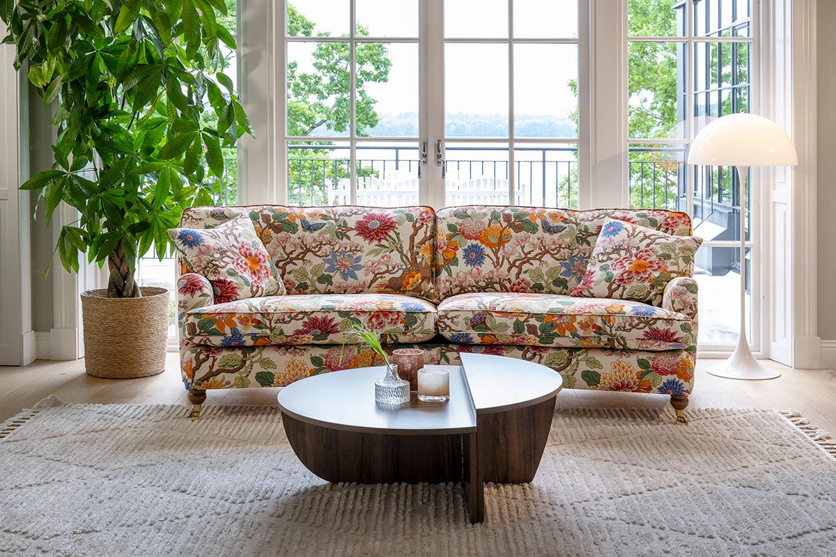 Split Sofabord i røget eg, der står på et beige, mønstret tæppe foran en blomstret sofa