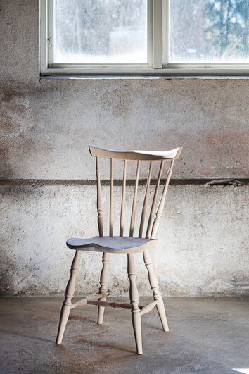 Classic Pindestol i klarlakeret birk i et rum med rå betonvæg og et vindue, der lukker dagslys ind