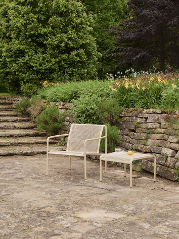 Dapple Loungestol og Dapple Loungebord 57x57 i farven Cashmere, som står på en stenbelagt udeplads