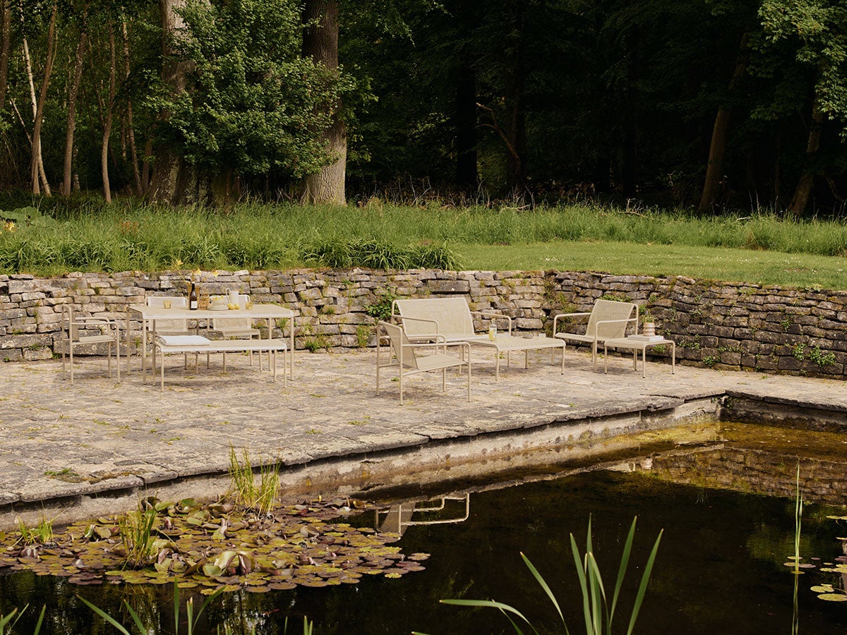 Loungeserien Dapple i farven Cashmere, som står på en stenbelagt udeplads ved siden af en dam