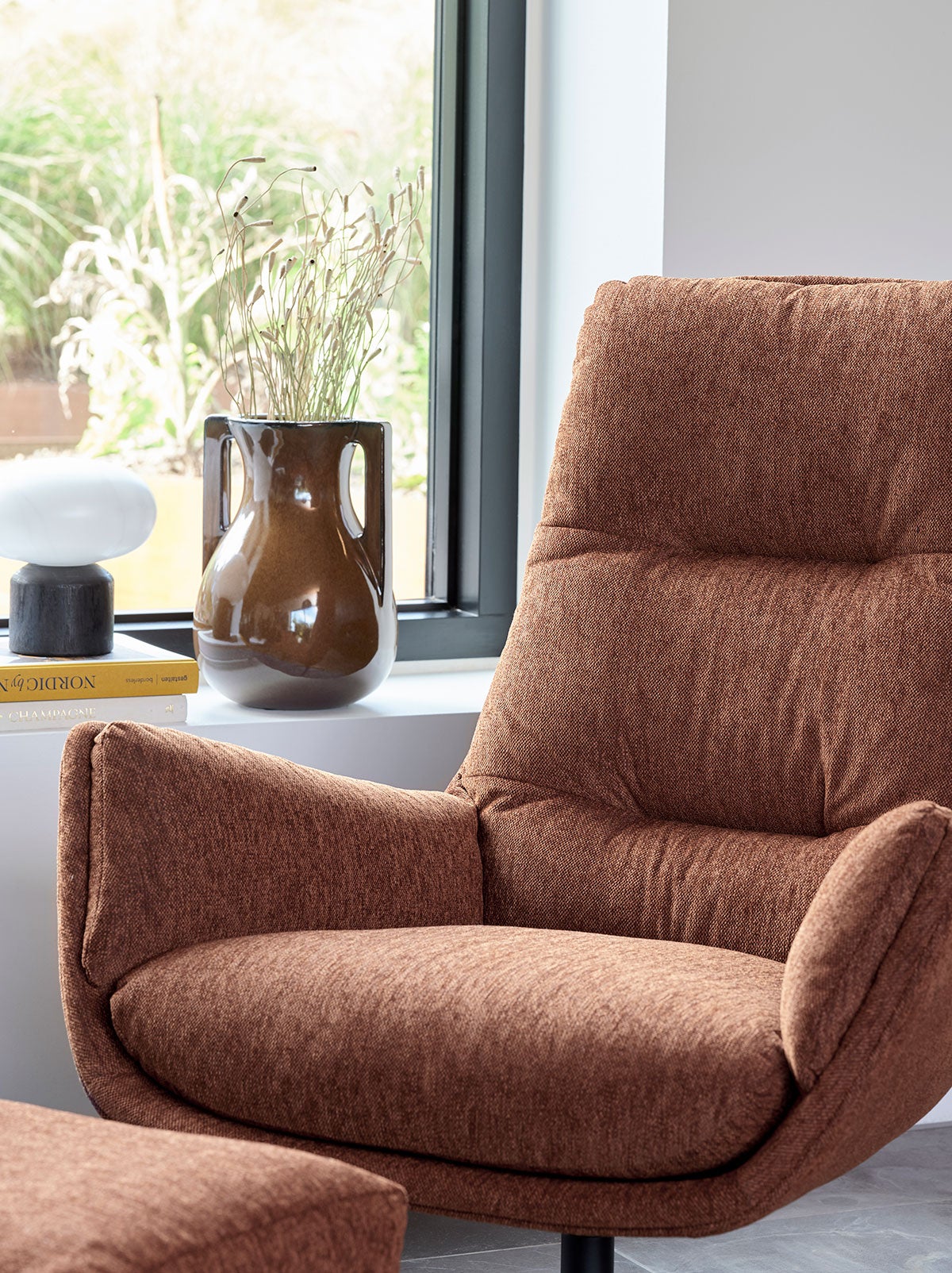 Moro Lænestol i stoffet Copparo Rusty Orange foran et vindue