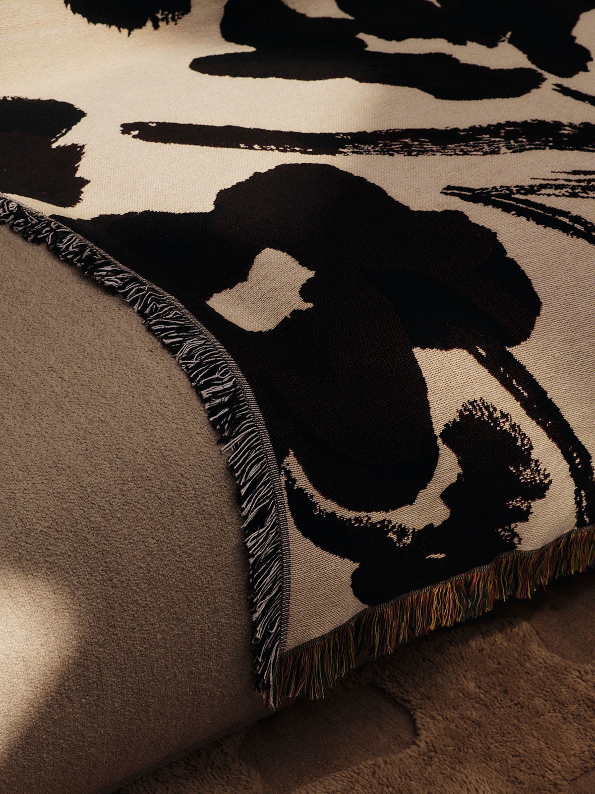 Cilla Tapestry Plaid i farven Off-White/Dark Grape, som ligger casually hen over sofakanten