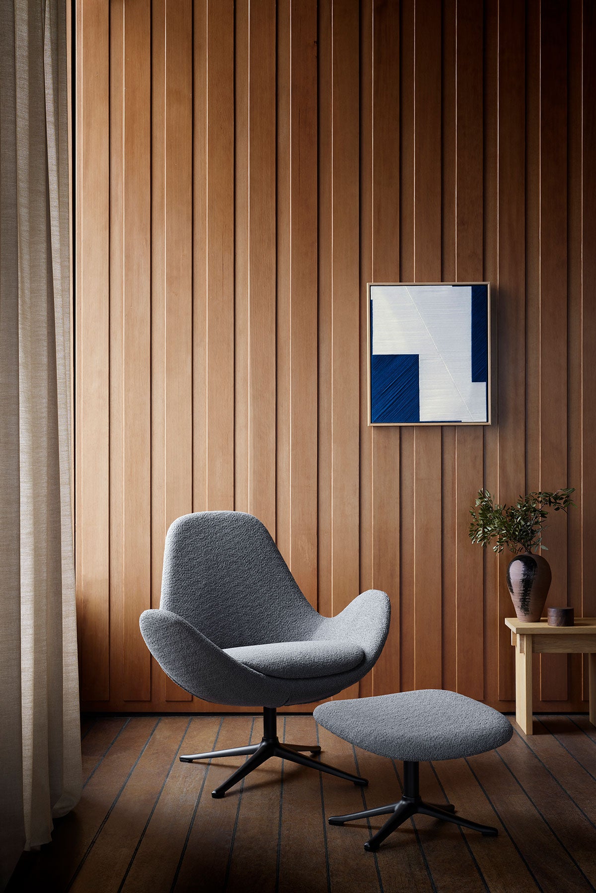 Ghost Low Lænestol og fodskammel i stoffet Bormio Soft Grey med ben i sort aluminium i rum med træbeklædte vægge