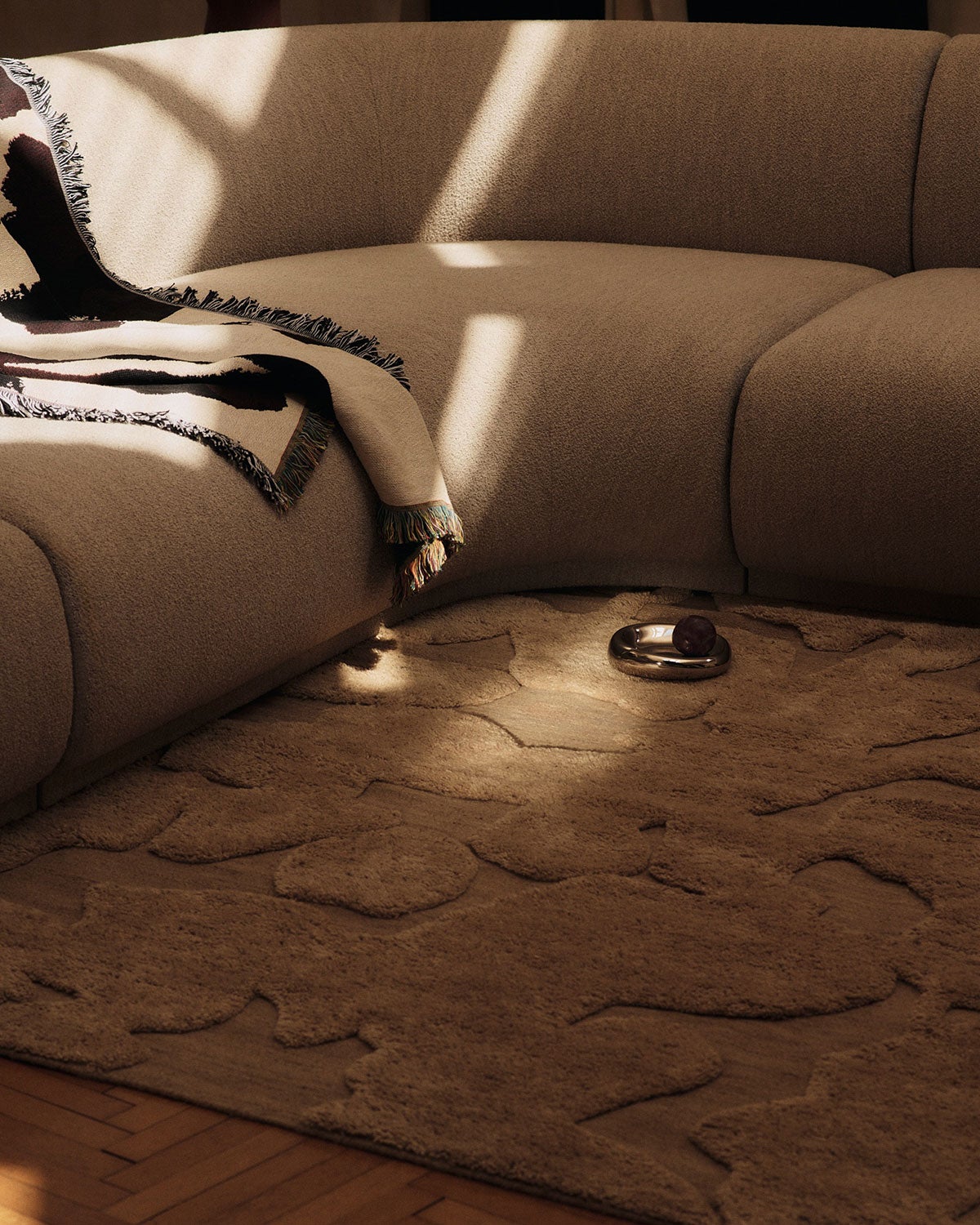 Cilla Tæppe i farven Tan under en beige hjørnesofa
