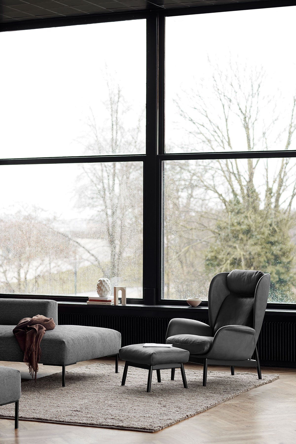 Padova Lænestol og fodskammel i læderet Nature Warm Stone Grey med sorte ben i moderne stue