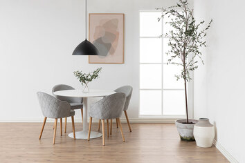 Ibiza Spisebord i hvid MDF med fire spisebordsstole i gråt stof som står i en lys spisestue