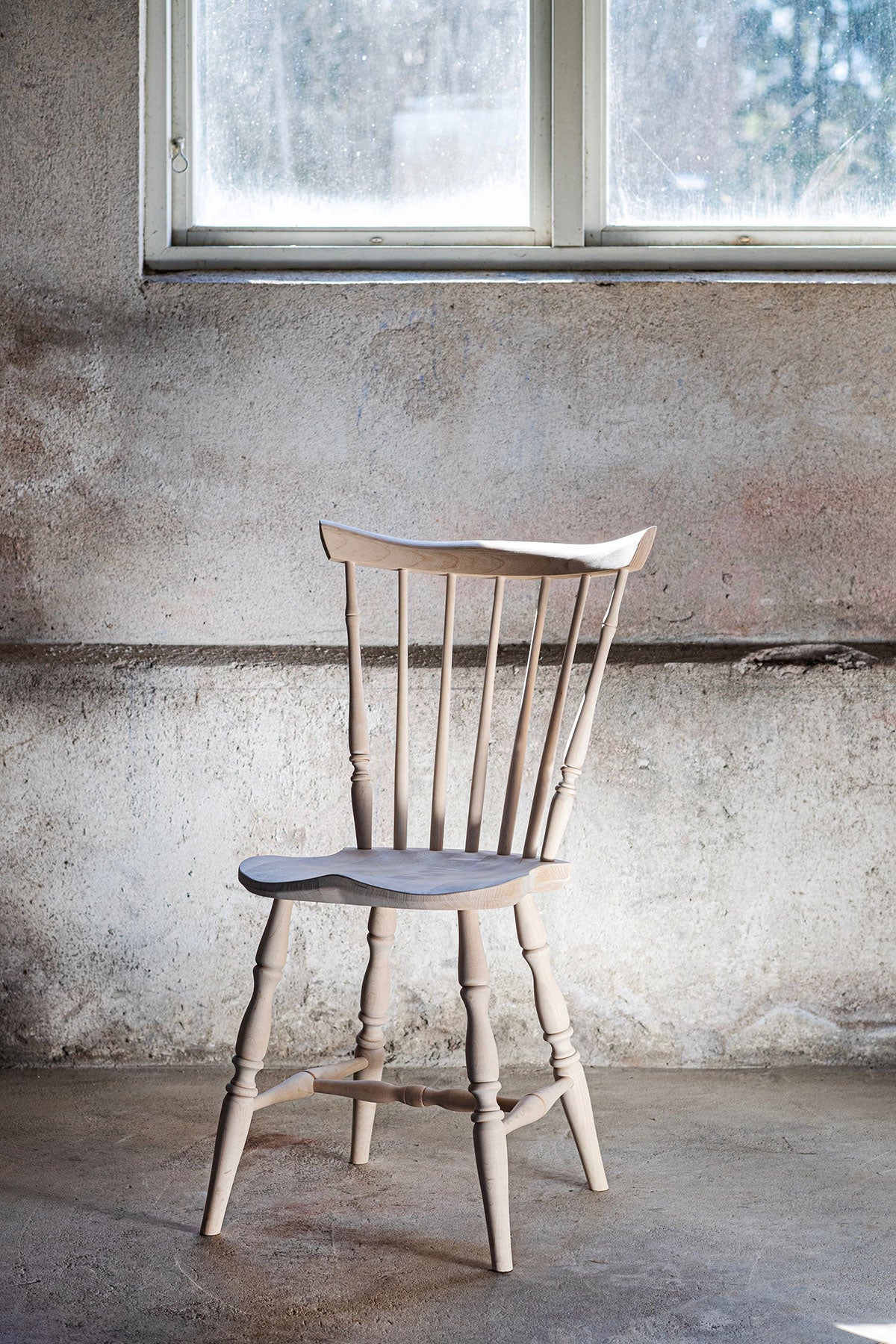 Classic Pindestol i klarlakeret birk i et rum med rå betonvæg og et vindue, der lukker dagslys ind