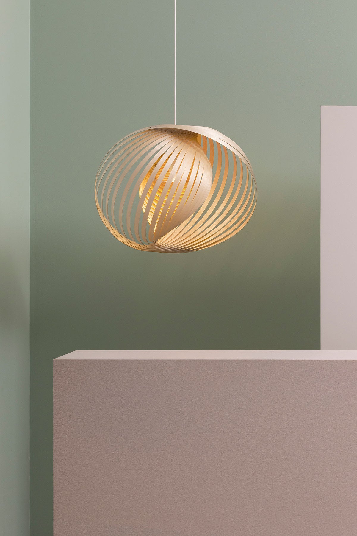 Adilo 8200 Loftlampe i birk, der hænger mod en lysegrøn væg