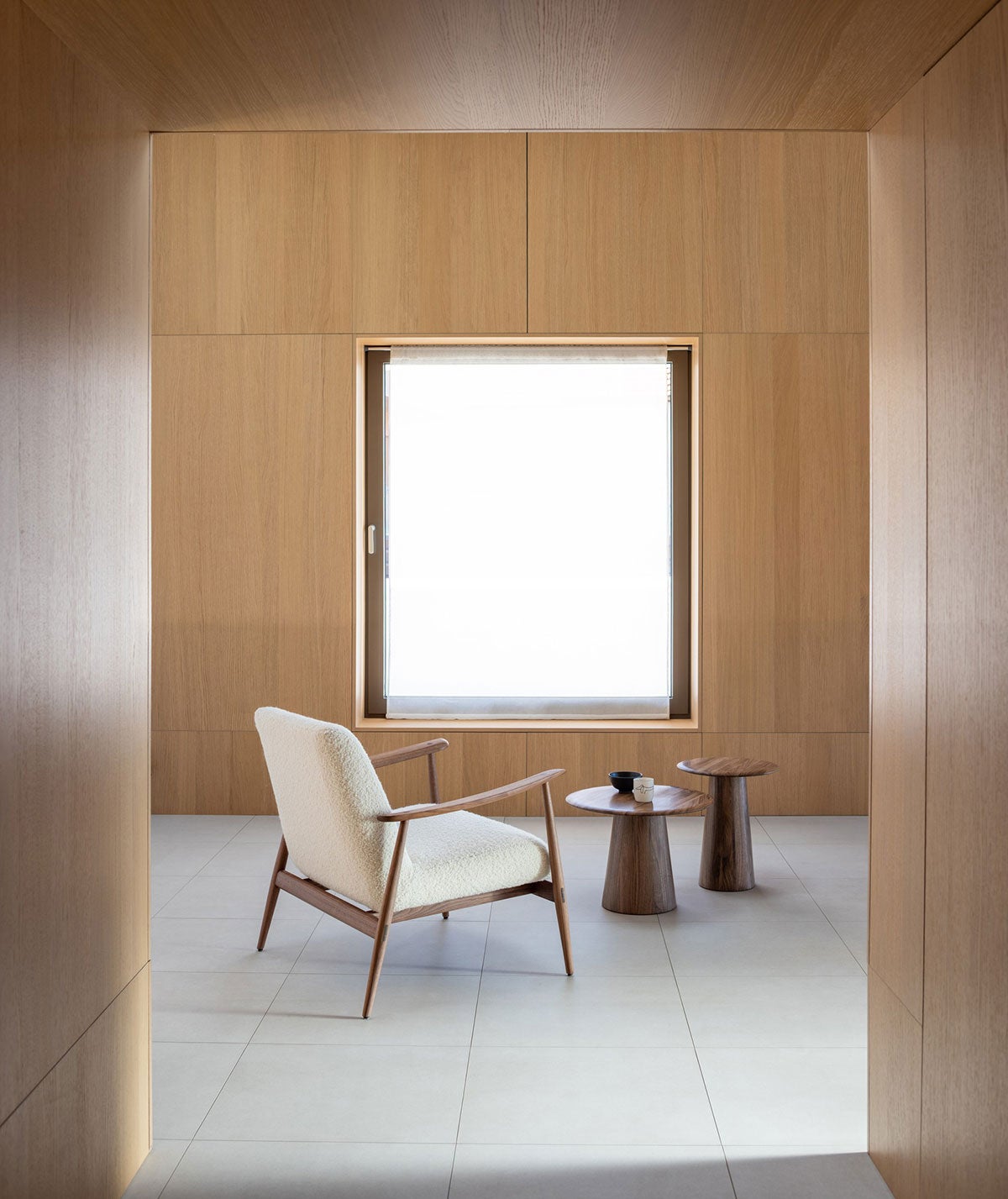 Aska Lounge Lænestol i olieret valnød med stofbetræk i Dedar Nimbus 6 i et rum med vægge af træpaneler