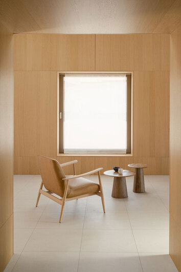 Aska Lounge Lænestol i hvidolieret eg betrukket med læderet Dakar Nature i et rum med vægge af træpaneler