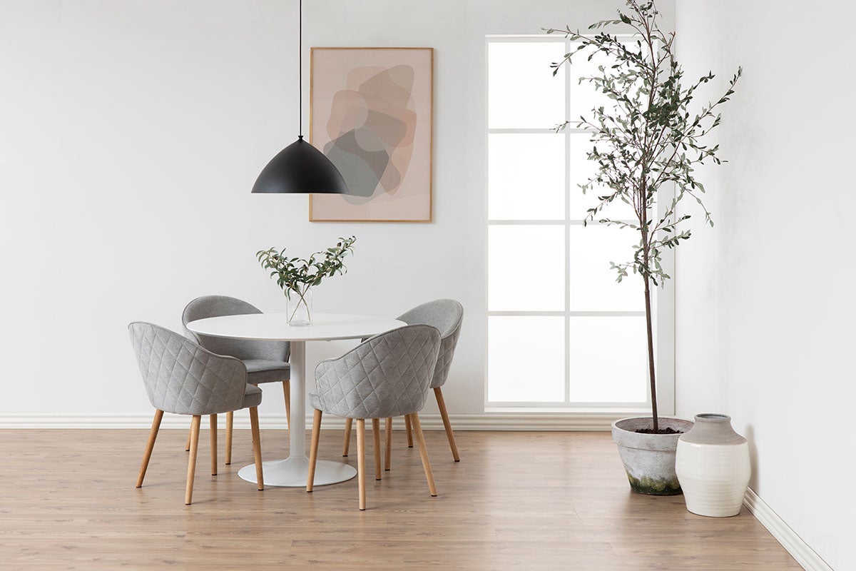 Ibiza Spisebord i hvid MDF med fire spisebordsstole i gråt stof som står i en lys spisestue